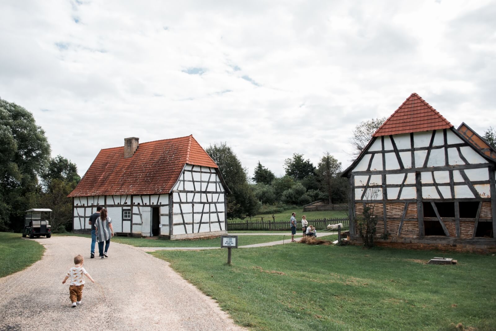 A family explores white farm building with red roofs on a farm.